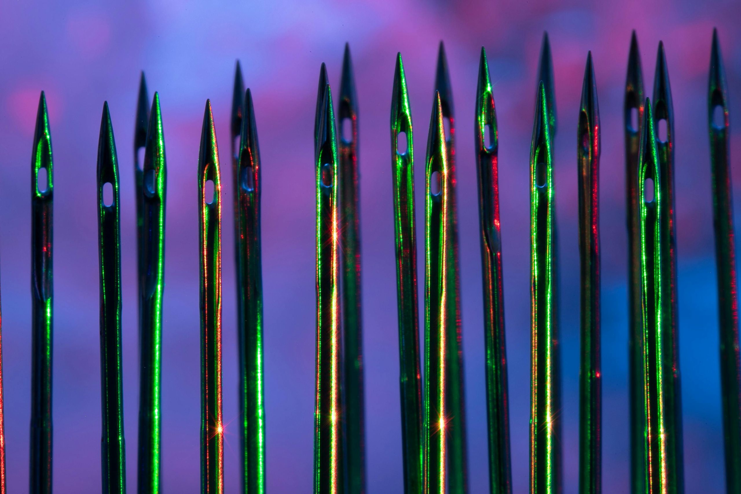 Bright, colorful close-up photo of sewing needles with abstract colorful lighting, showcasing a creative pattern.